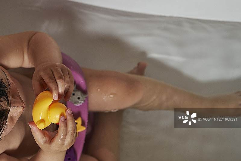 快乐的宝宝在浴室玩肥皂泡，泡沫浴中的小黄鸭图片素材