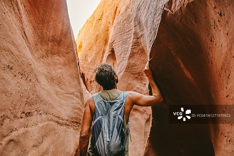 夏天，年轻男人在埃斯卡兰特探索狭窄的峡缝型峡谷图片素材