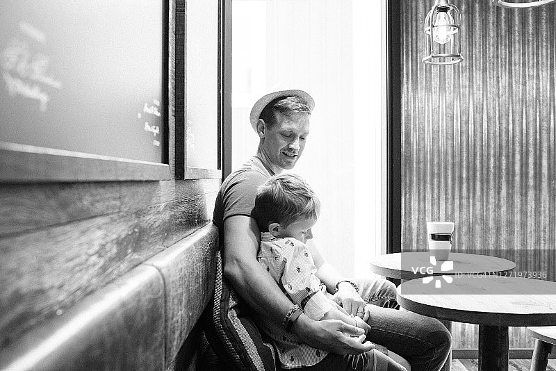 父亲在咖啡馆里抱着儿子喝咖啡图片素材