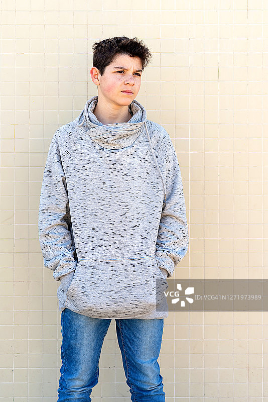 黄色墙壁前看向别处的少年肖像图片素材