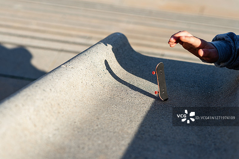 在户外斜坡上玩迷你滑板或手指滑板图片素材