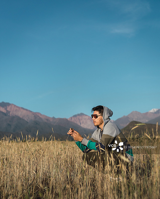 年轻男人坐在田野里安第斯山脉旁图片素材