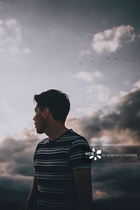 眺望云层间地平线的年轻男子图片素材