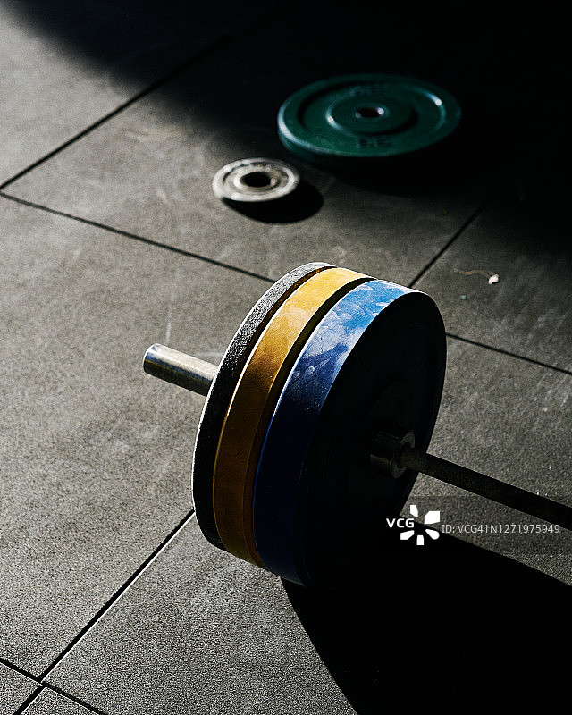 室内健身房橡胶地板上的蓝、黄、黑色重型圆盘图片素材