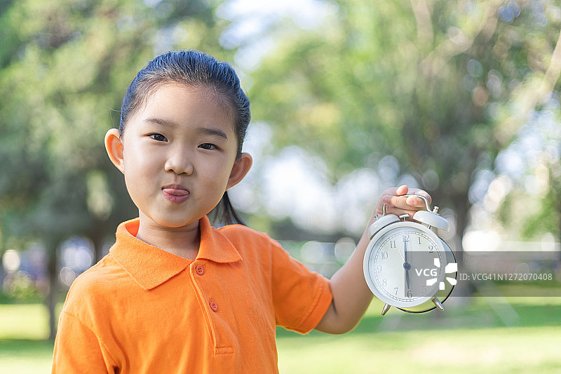 可爱的小女孩拿着一个时钟图片素材