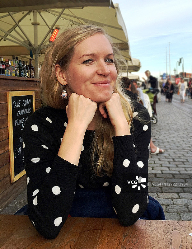 年轻女子在哥本哈根老港的咖啡馆里微笑。图片素材