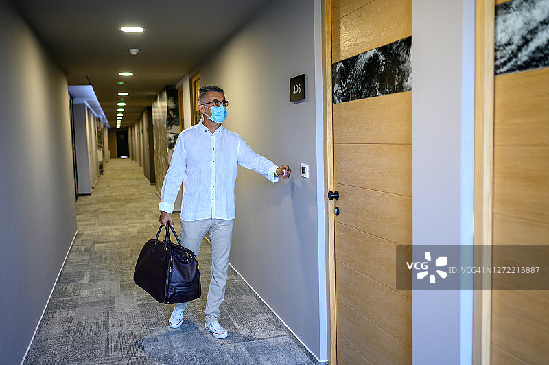 在酒店走廊里戴防护口罩的男人图片素材