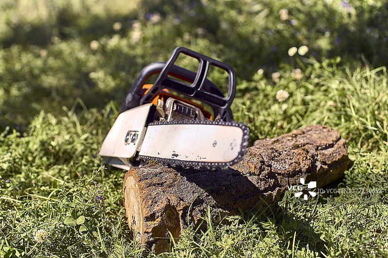 草地上原木上的油锯图片素材
