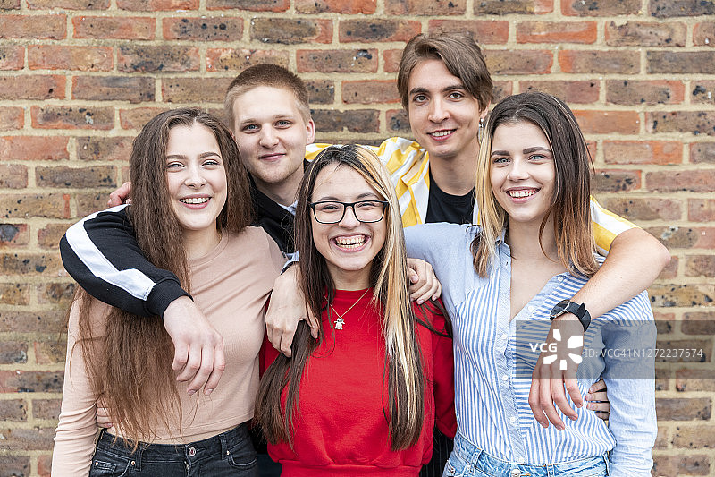 靠在砖墙上的快乐男女朋友图片素材