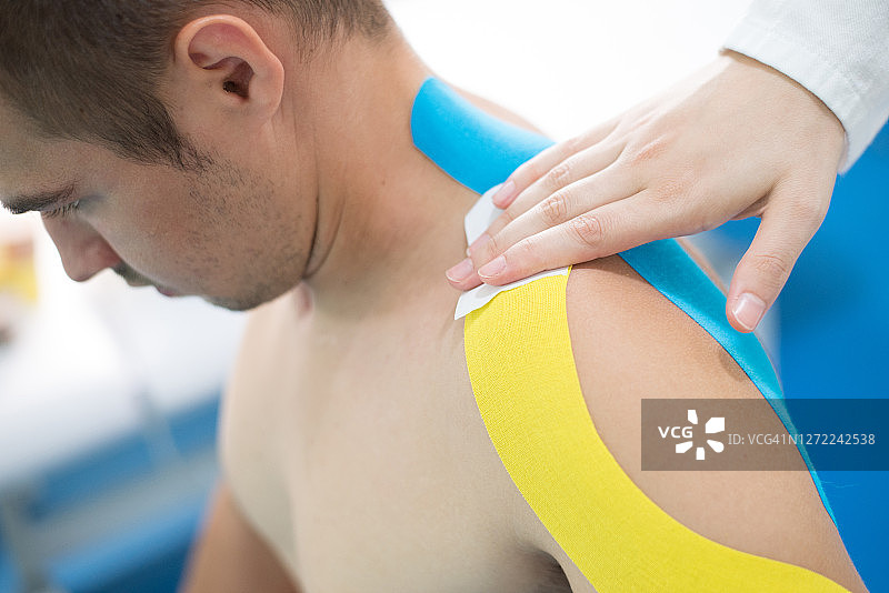理疗师在受伤的手臂上贴弹性治疗胶带图片素材