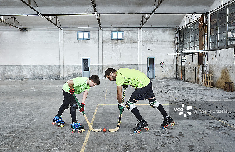 父子在球场上玩轮滑曲棍球图片素材