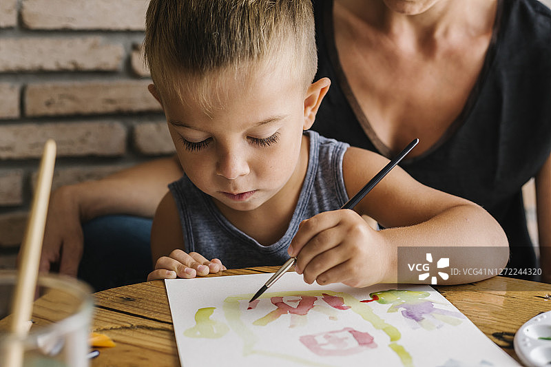 在家和母亲一起在纸上绘画的男孩图片素材