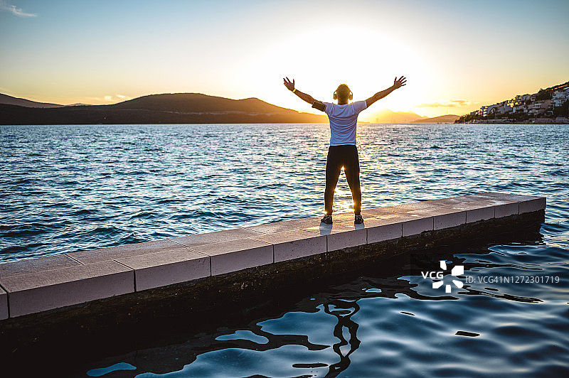 在海边日落时张开双臂的中年男人图片素材