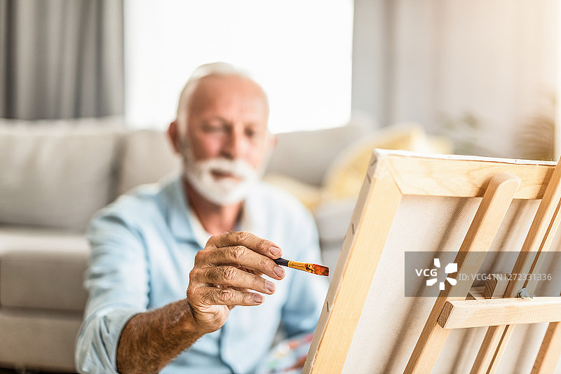 老年男人在客厅里画布上绘画图片素材