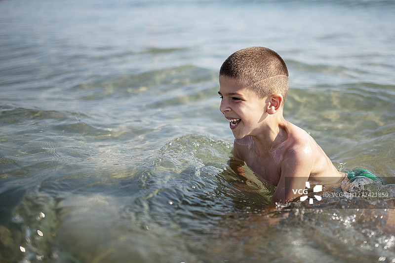 坐在海里的小男孩开怀大笑图片素材