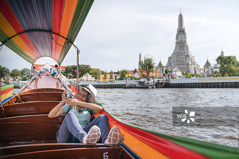 少女游客乘长尾船拍摄城市风光图片素材