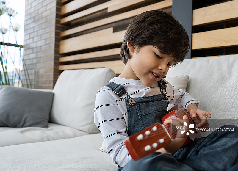快乐的小男孩在弹吉他图片素材