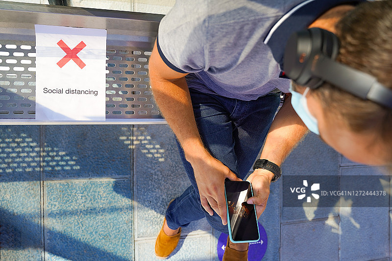 男人坐在公交车站等候，保持社交距离图片素材