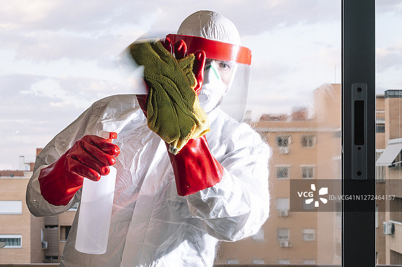 身穿全套防护服的医生正在家中清洁图片素材