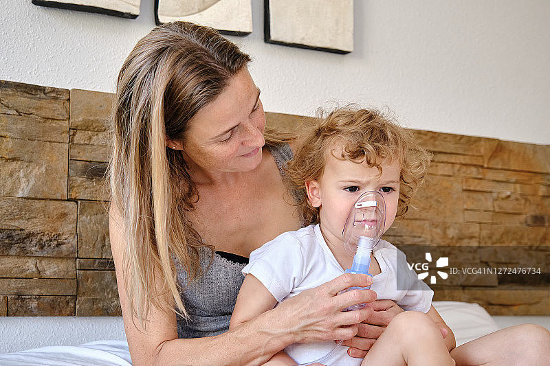 母亲帮助孩子使用雾化器图片素材