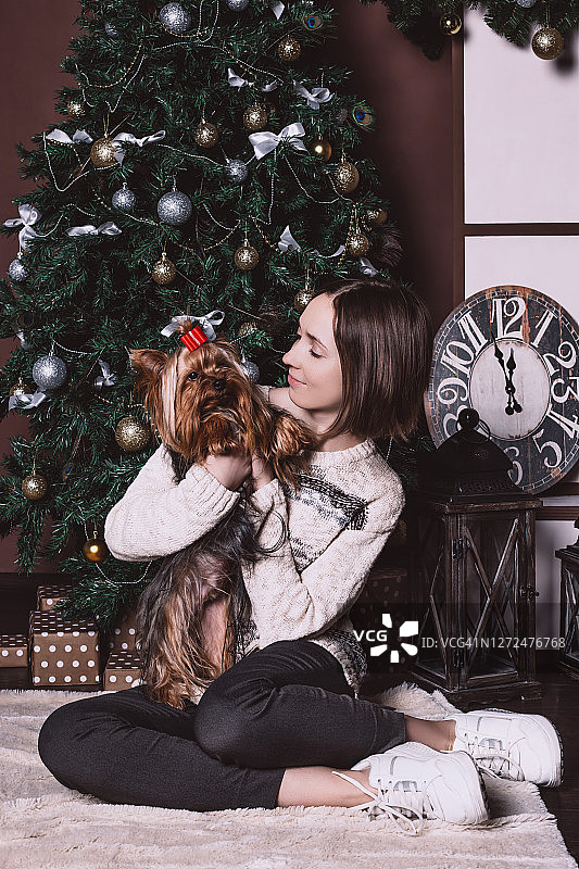 一位身着休闲装的年轻女子抱着一只漂亮的约克夏犬图片素材