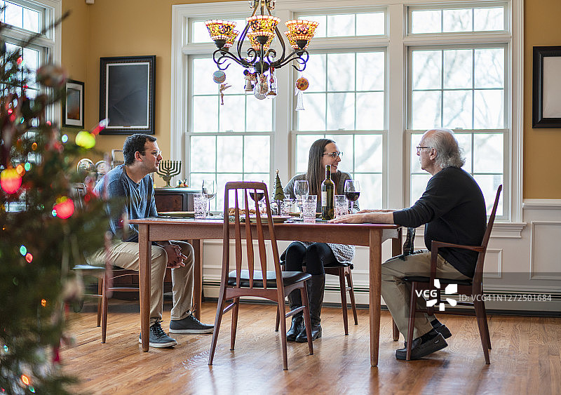 圣诞晚餐时围坐在桌旁的二代家庭图片素材