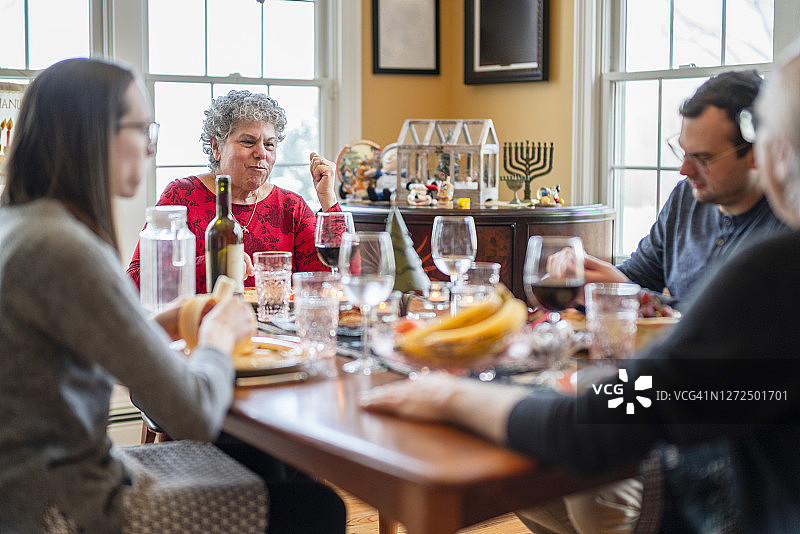 两代多元文化家庭在客厅共度节日晚餐，客厅装饰有圣诞节和光明节的装饰图片素材