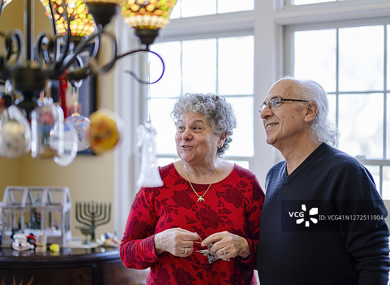 老年夫妇装饰他们的房子，准备过冬日圣诞节和光明节图片素材