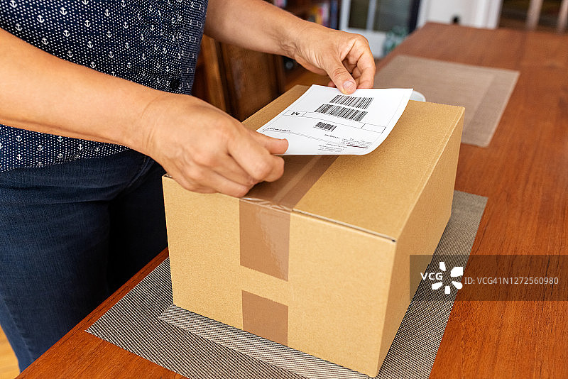 女人在纸板上贴标签准备发货图片素材