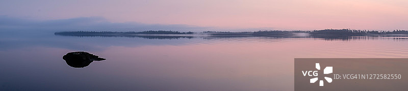 秋日薄雾中平静的湖面和岩石岸边全景图片素材