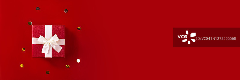红色背景金色纸屑上的红色礼品盒banner图片素材
