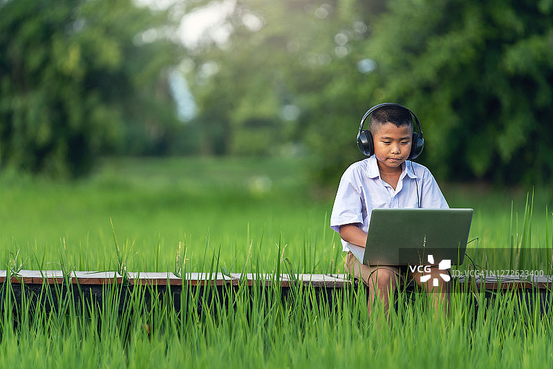 使用笔记本电脑在线学习的亚洲男孩，新常态在线教育图片素材