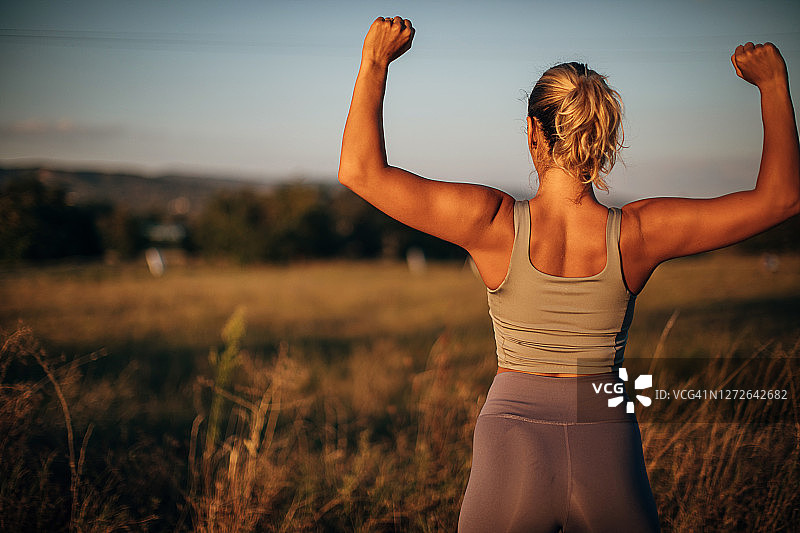 一位年轻健康女人在户外展示肌肉图片素材