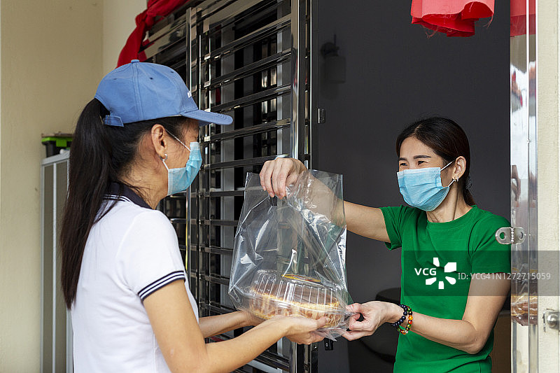 配送员佩戴口罩为住宅区女性送货图片素材