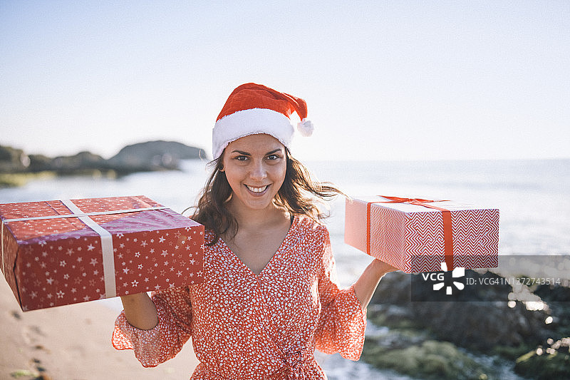 微笑的女子在海滩上拿着圣诞礼物图片素材