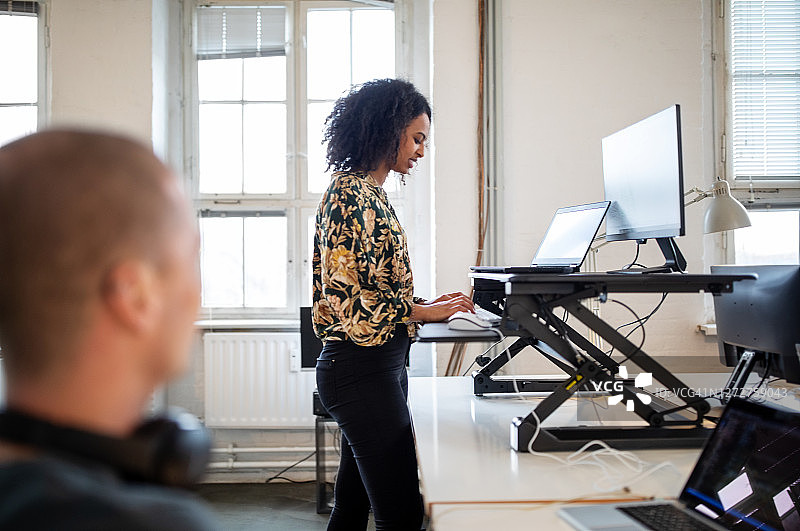 在符合人体工程学的站立式办公桌前工作的女人图片素材