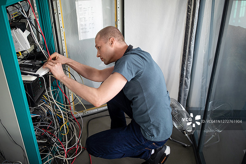 IT技术员在办公室服务器机房修理电缆图片素材