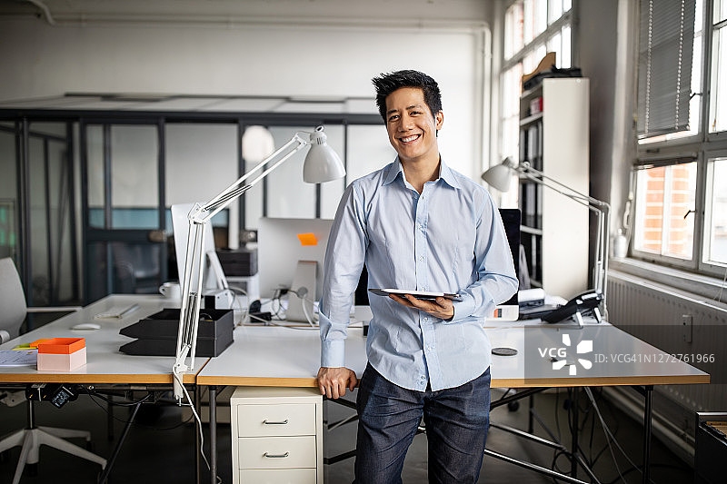 手持平板电脑的年轻亚洲商人肖像图片素材