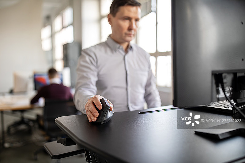 在办公室站立办公桌前工作的成熟男人图片素材