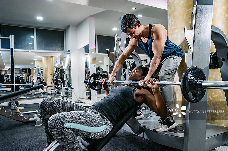 健身教练帮助女士在健身房锻炼图片素材