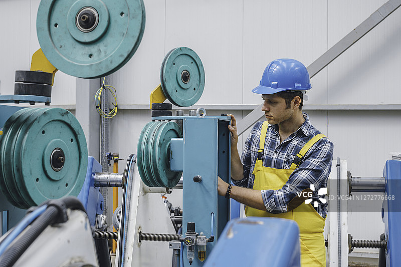 工厂里操作球阀的年轻工人图片素材