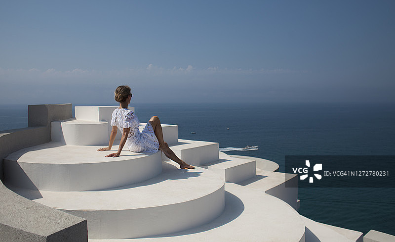 坐在后现代建筑屋顶欣赏海景的女人图片素材