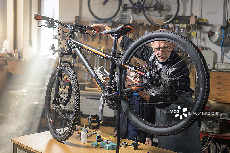 资深自行车修理工教孙子修理自行车图片素材