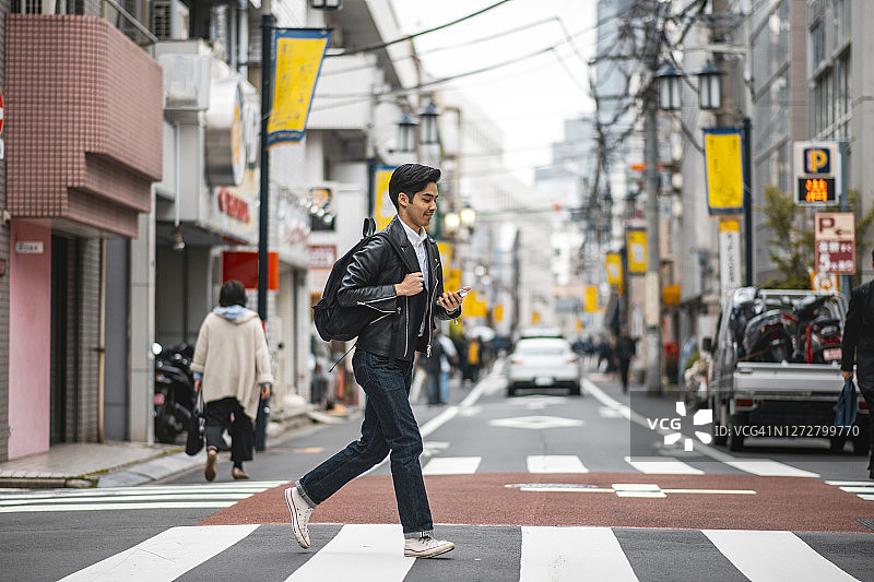 背着背包奔跑在东京街头的日本年轻男子图片素材
