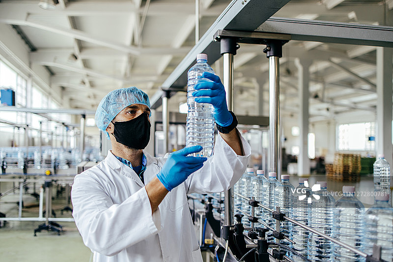 在灌装厂戴防护面罩进行质检的男人图片素材