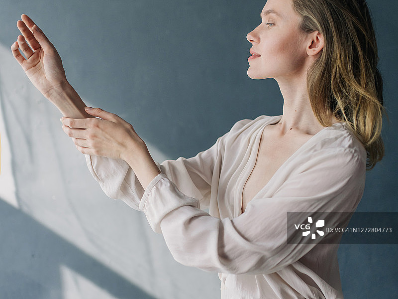 在蓝色背景下摆姿势的年轻梦幻女性图片素材