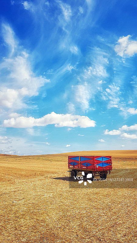 收割后的谷物田野上的彩色农用拖车图片素材