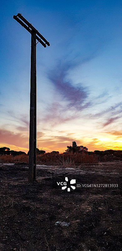 暮光下的烧毁木制电线杆与绚丽背景图片素材