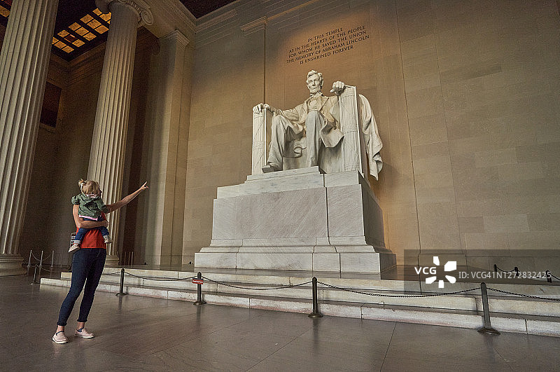 母亲和幼儿女儿在林肯纪念堂，背景是美国首都华盛顿特区的华盛顿纪念碑图片素材