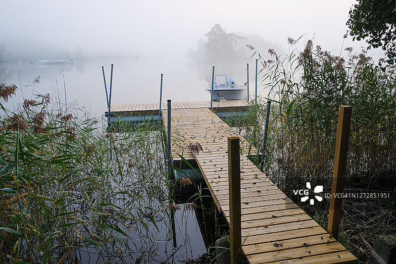 雾蒙蒙的秋日清晨：湖边停靠着游船的码头图片素材